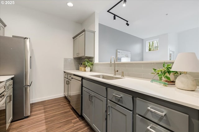 kitchen featuring gray cabinetry, decorative backsplash, appliances with stainless steel finishes, dark wood-style floors, and a sink