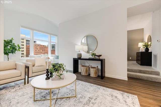 living room featuring stairway, wood finished floors, visible vents, baseboards, and lofted ceiling