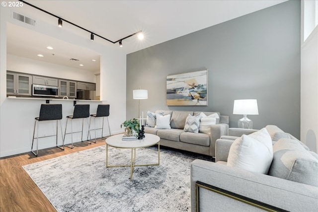 living room with recessed lighting, wood finished floors, visible vents, and baseboards