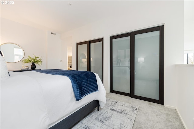 bedroom featuring baseboards, carpet flooring, two closets, and visible vents