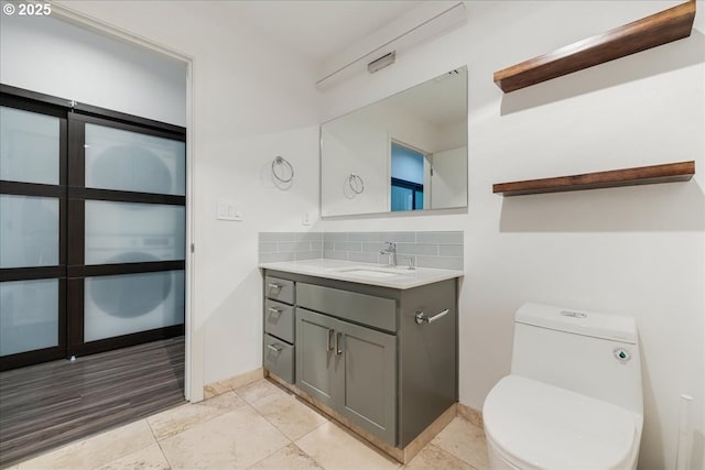 bathroom featuring decorative backsplash, toilet, and vanity