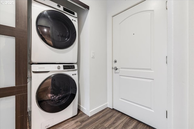 laundry room with baseboards, stacked washer and dryer, dark wood-style flooring, and laundry area