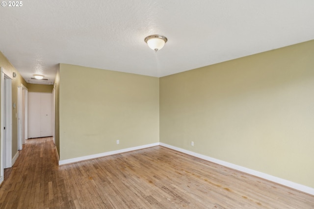 spare room with a textured ceiling and light wood-type flooring