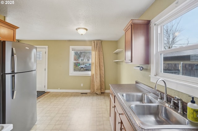 kitchen with stainless steel fridge, sink, and a textured ceiling