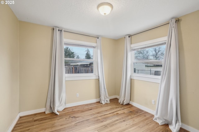 spare room with a textured ceiling and light wood-type flooring