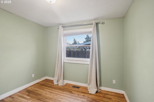 spare room with a textured ceiling and light hardwood / wood-style flooring