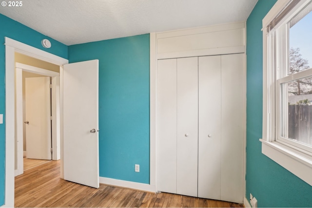 unfurnished bedroom featuring a textured ceiling, light hardwood / wood-style floors, and a closet