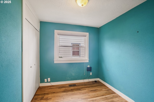 unfurnished room featuring light hardwood / wood-style flooring and a textured ceiling