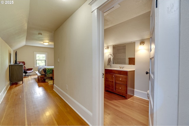 8113 SE Morrison St, Portland, OR 97215 - hallway with light wood-style floors, vaulted ceiling, a sink, and baseboards