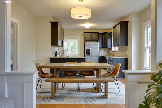 8113 SE Morrison St, Portland, OR 97215 - kitchen featuring stainless steel refrigerator with ice dispenser, decorative backsplash, light countertops, light wood-type flooring, and dark brown cabinetry