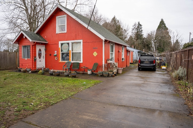 view of front facade featuring a front yard, fence, driveway, and entry steps