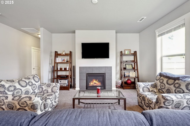 living area featuring visible vents, carpet, and a tile fireplace