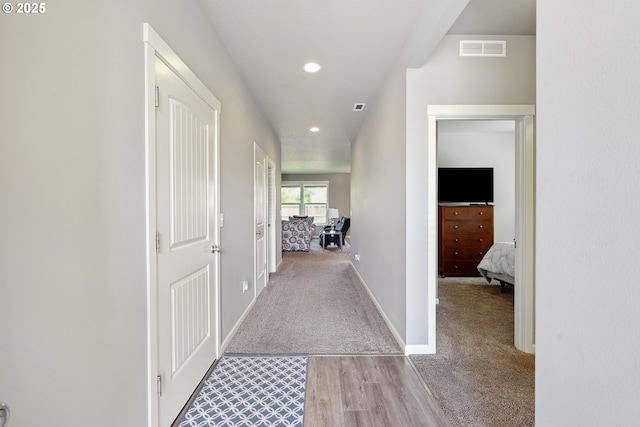 hall featuring carpet floors, recessed lighting, baseboards, wood finished floors, and visible vents