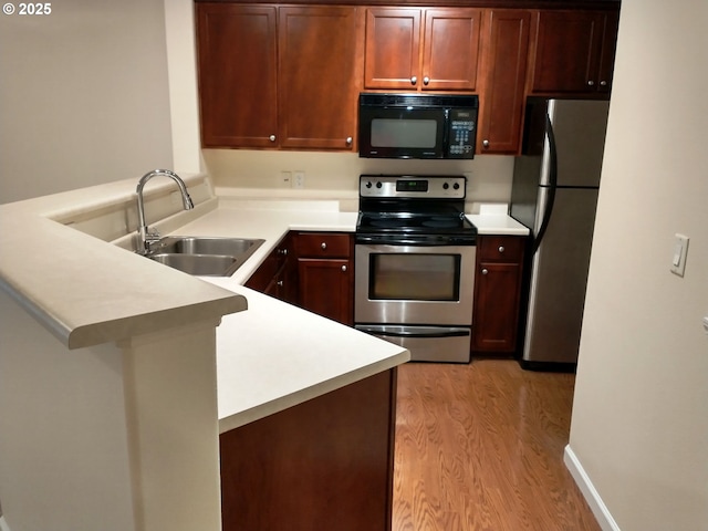 kitchen with light hardwood / wood-style floors, sink, kitchen peninsula, and stainless steel appliances