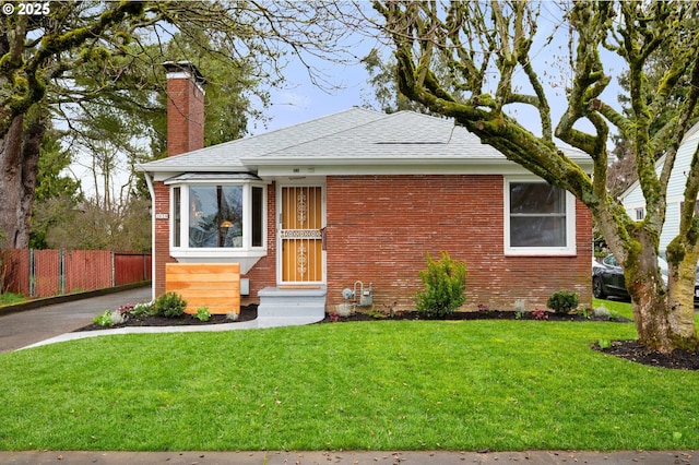 view of front of house featuring a front yard, fence, a chimney, entry steps, and brick siding