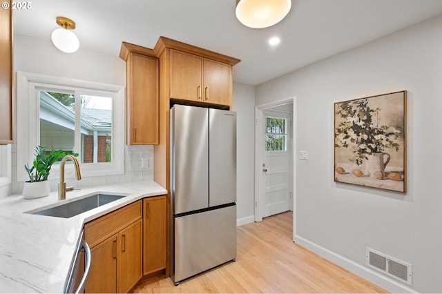 kitchen with visible vents, decorative backsplash, appliances with stainless steel finishes, light wood-style floors, and a sink