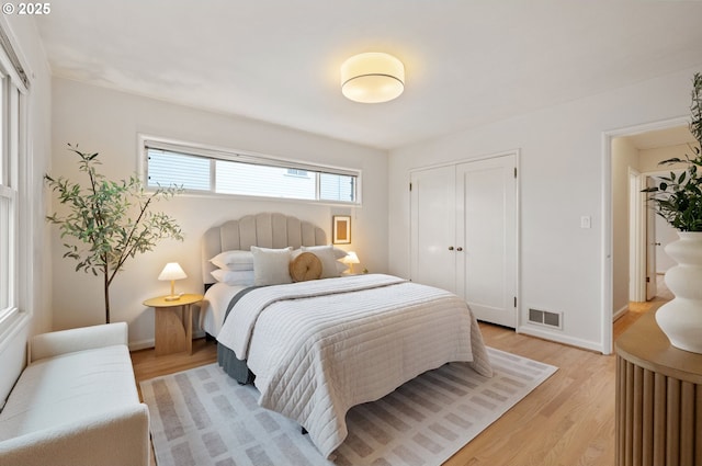 bedroom featuring a closet, visible vents, light wood-style flooring, and baseboards