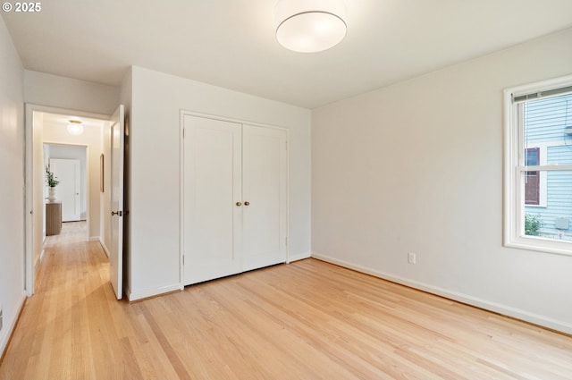 unfurnished bedroom with light wood-style floors, baseboards, and a closet