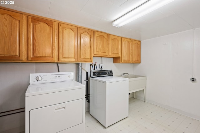 laundry room with a sink, cabinet space, light floors, and washing machine and dryer