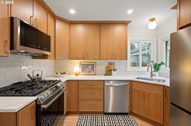 kitchen featuring a sink, recessed lighting, stainless steel appliances, light wood-style floors, and decorative backsplash