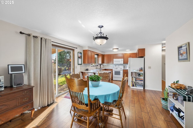 dining area with sink, hardwood / wood-style floors, and a textured ceiling