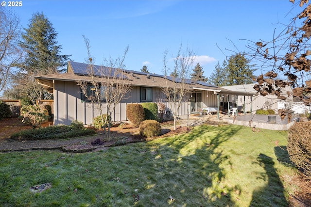 rear view of house featuring a lawn, a patio, and solar panels