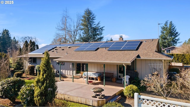 back of property featuring a wooden deck and solar panels