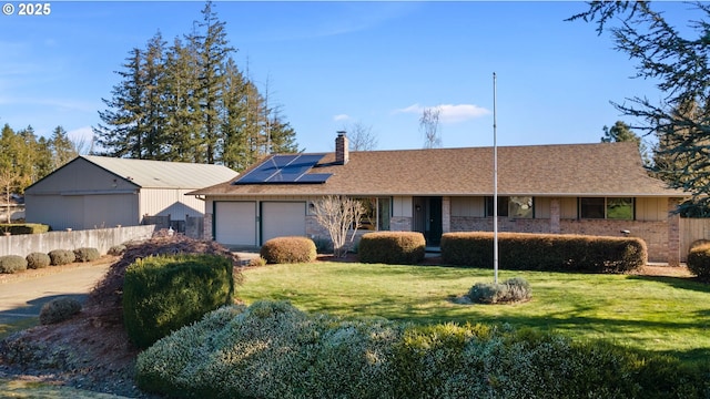 ranch-style house with a garage, a front yard, and solar panels