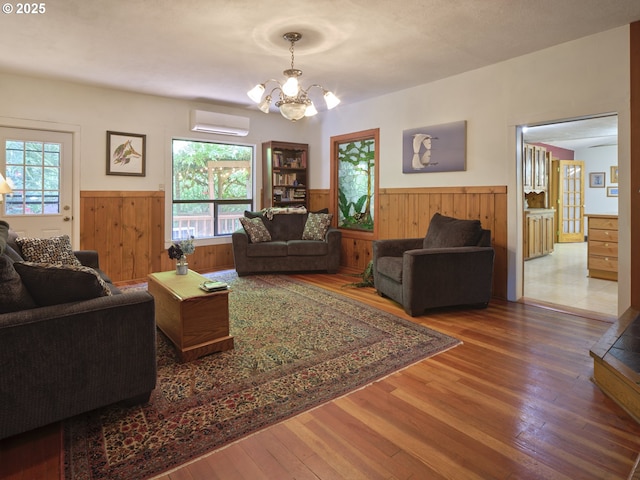 205 Baker Rd, Ariel, WA 98603 - living area with wainscoting, a wall unit AC, wood walls, hardwood / wood-style floors, and a chandelier