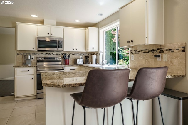 2614 NE 176th Ave, Vancouver, WA 98684 - kitchen featuring appliances with stainless steel finishes, a peninsula, tasteful backsplash, light stone countertops, and recessed lighting