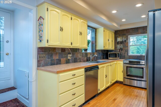 10001 SW 35th Ave, Portland, OR 97219 - kitchen featuring appliances with stainless steel finishes, light countertops, light wood-type flooring, tasteful backsplash, and recessed lighting
