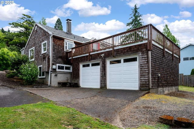 10001 SW 35th Ave, Portland, OR 97219 - view of home's exterior featuring driveway, a chimney, an attached garage, and a deck