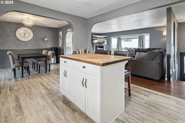 3780 SE 21st Dr, Gresham, OR 97080 - kitchen featuring butcher block counters, arched walkways, open floor plan, light wood-type flooring, and white cabinetry