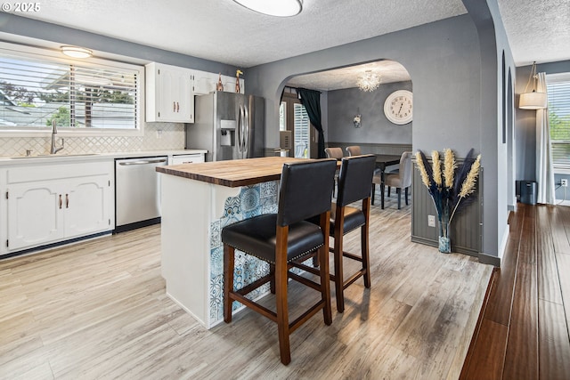 3780 SE 21st Dr, Gresham, OR 97080 - kitchen with stainless steel appliances, arched walkways, a sink, a textured ceiling, and a breakfast bar area