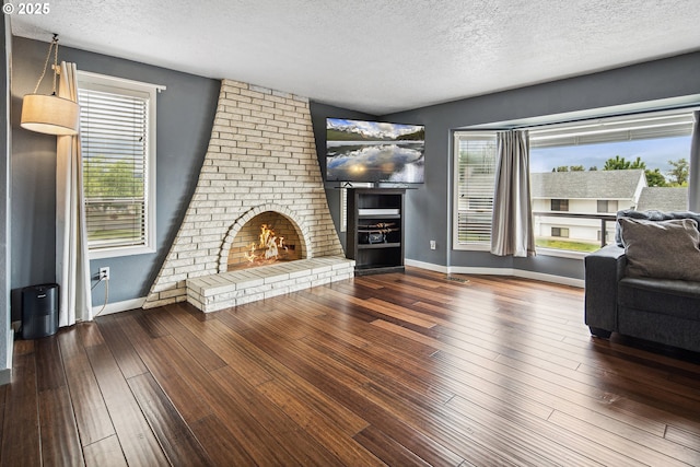 3780 SE 21st Dr, Gresham, OR 97080 - unfurnished living room with a textured ceiling, hardwood / wood-style flooring, a brick fireplace, and baseboards