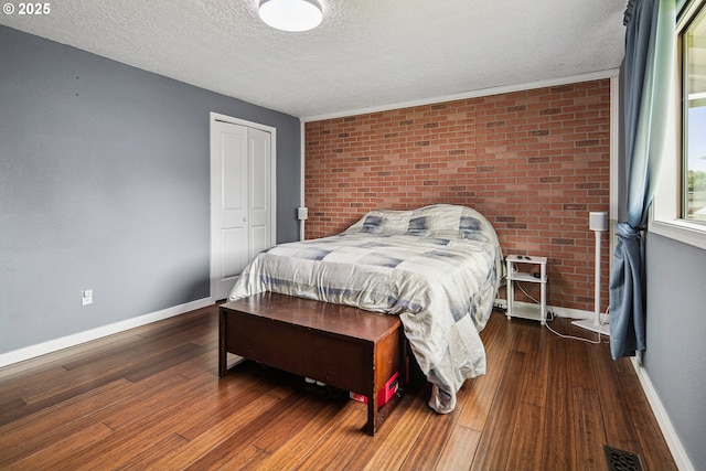 3780 SE 21st Dr, Gresham, OR 97080 - bedroom with a textured ceiling, baseboards, brick wall, wood finished floors, and a closet