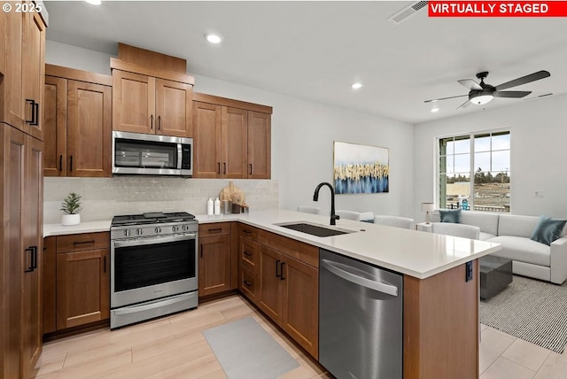 kitchen featuring tasteful backsplash, sink, ceiling fan, kitchen peninsula, and stainless steel appliances