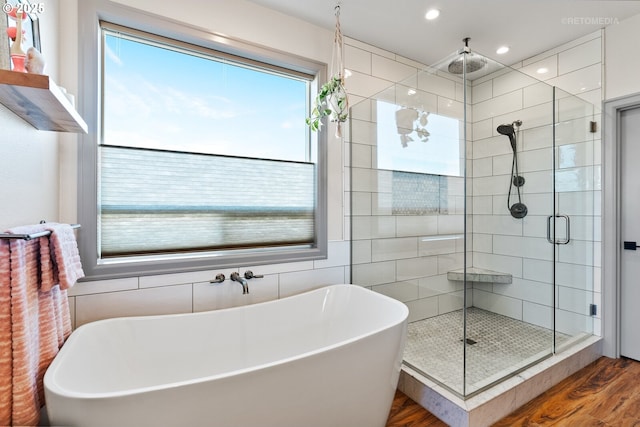 bathroom featuring recessed lighting, a freestanding tub, a shower stall, and wood finished floors