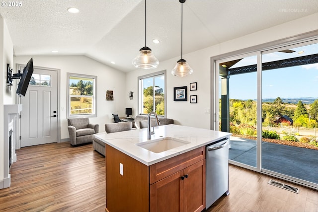 kitchen with visible vents, brown cabinetry, dishwasher, decorative light fixtures, and a sink