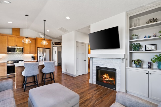 living room with visible vents, vaulted ceiling, dark wood finished floors, and a stone fireplace