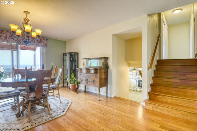 dining area with stairway, wood finished floors, and a notable chandelier