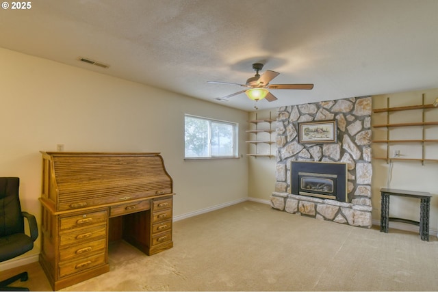 unfurnished office featuring a fireplace, carpet, a ceiling fan, baseboards, and visible vents
