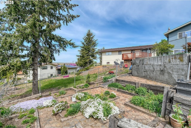 view of yard with fence, a wooden deck, and a vegetable garden