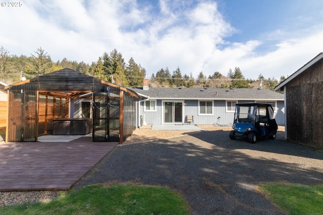 rear view of property with a hot tub and a deck