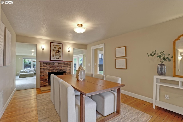 10455 NW Laidlaw Rd, Portland, OR 97229 - dining room with light wood-type flooring, a stone fireplace, and a textured ceiling