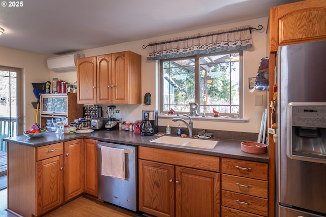 kitchen featuring sink, light hardwood / wood-style flooring, an AC wall unit, kitchen peninsula, and stainless steel appliances