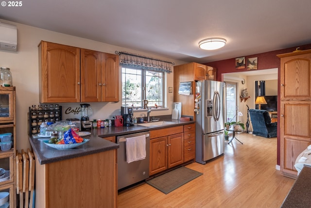 kitchen featuring appliances with stainless steel finishes, sink, a wall unit AC, and light wood-type flooring