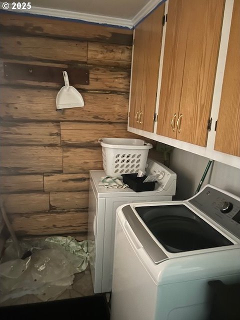 clothes washing area featuring cabinets, separate washer and dryer, and wood walls