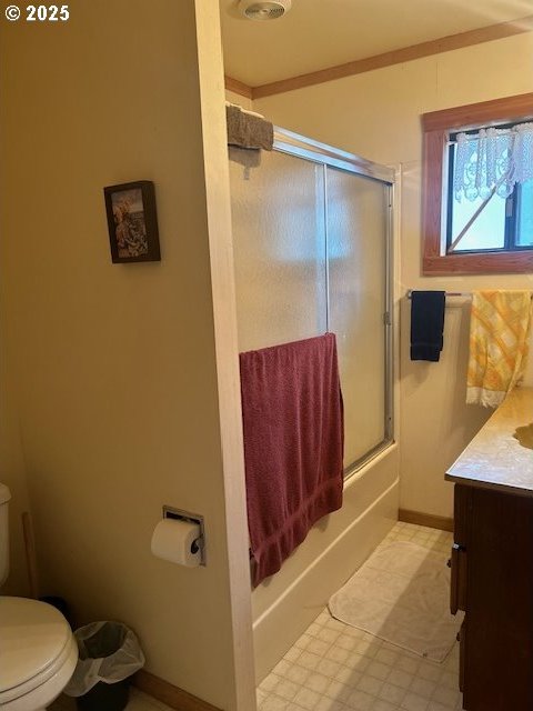 full bathroom with vanity, bath / shower combo with glass door, and toilet