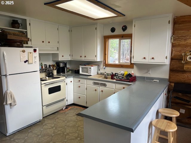 kitchen featuring ventilation hood, white cabinetry, rustic walls, kitchen peninsula, and white appliances